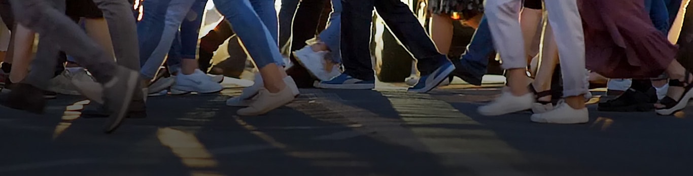 En fodgængerfelt i en by, der viser snesevis af mennesker, der går i hver sin retning, når de krydser gaden