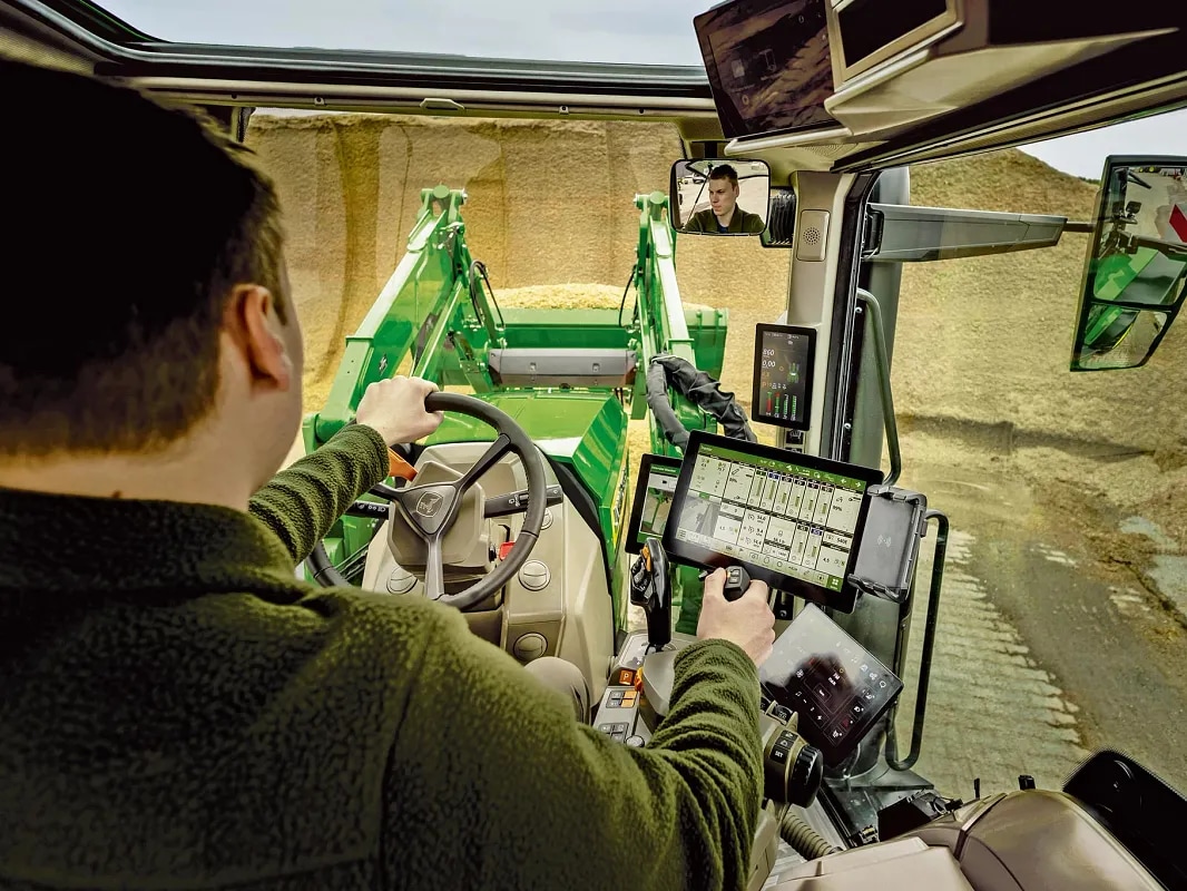 John Deere-traktor set indvendigt fra førerhuset med førerbetjeningselementer og frontlæsserbetjening.