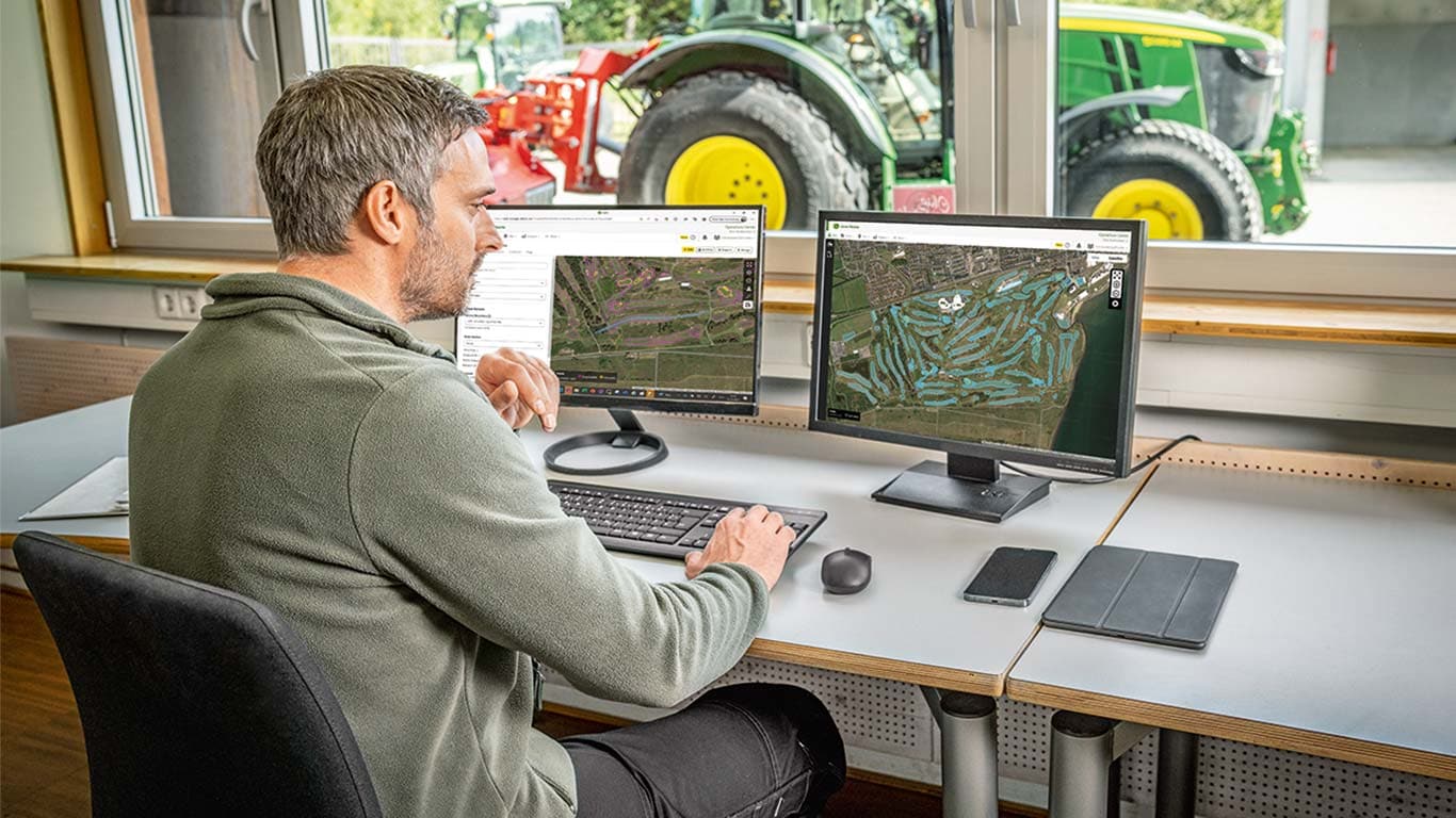 En greenkeeper ser på kort over en golfbane på sin computer.