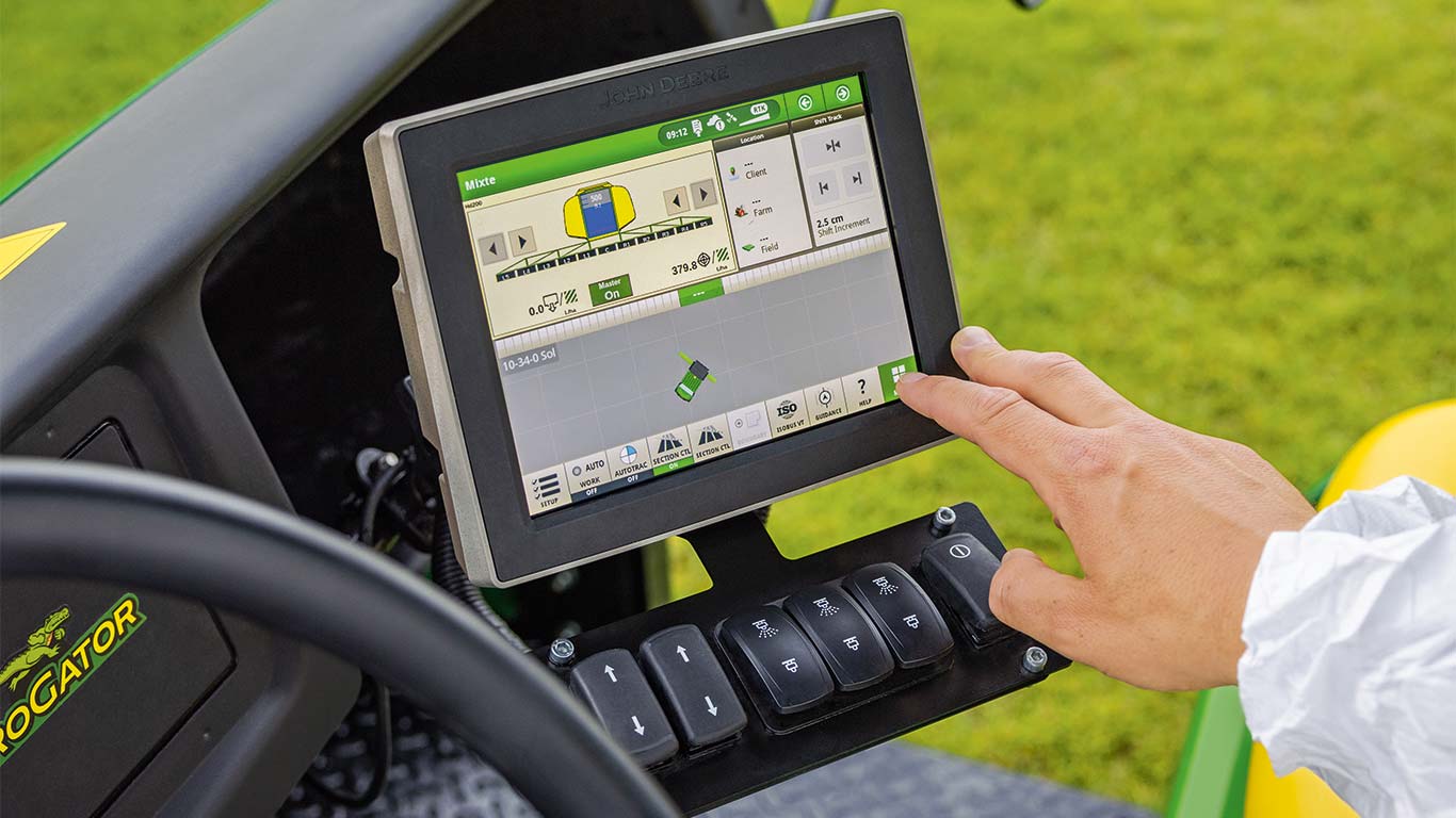En greenkeeper bruger skærmen i sin John Deere plæneklipper til at justere maskinen til den aktuelle opgave.