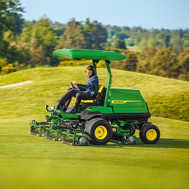 En greenkeeper arbejder på et græsområde med en John Deere-fairwayklipper