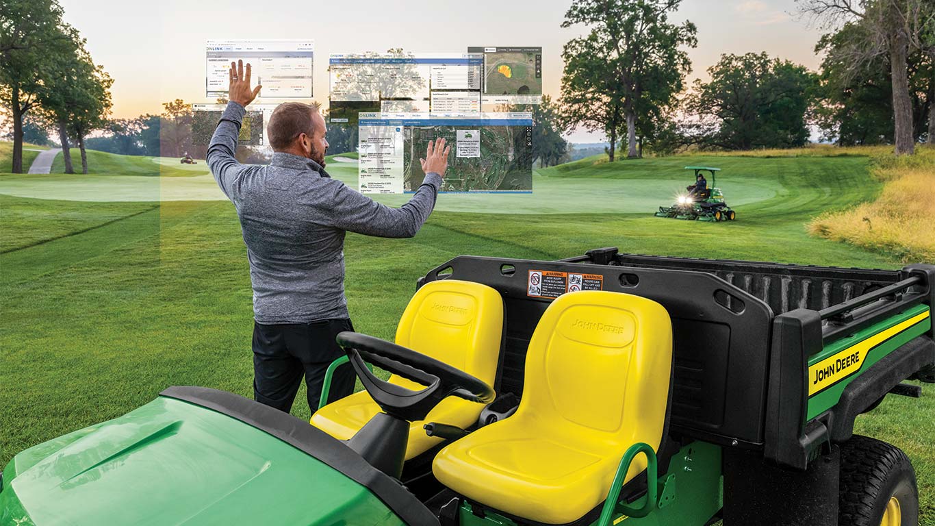 En greenkeeper betjener fiktive Smart Green Keeping-skærme trådløst på en golfbane.
