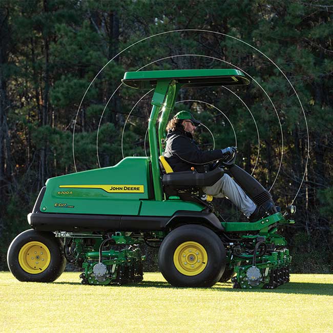 En greenkeeper arbejder på et græsområde med en John Deere-fairway-klipper og bruger opkoblingsteknologi.