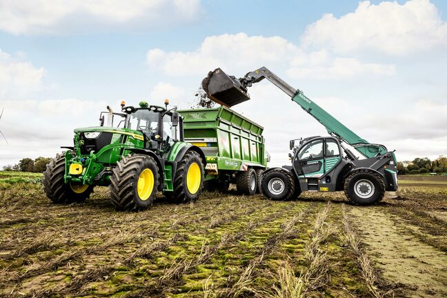 John Deere traktor, der læsser en grøn trailer med en teleskoplæsser under markarbejde