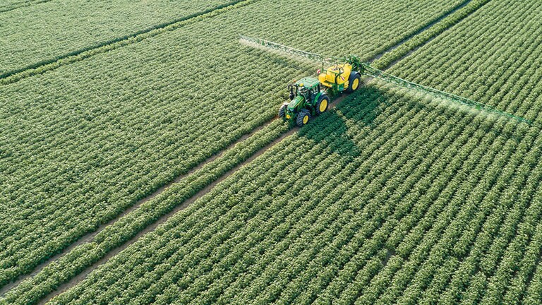 John Deere 6M Serie traktor tr&aelig;kkende M700 trailerspr&oslash;jte i kartoffelmark