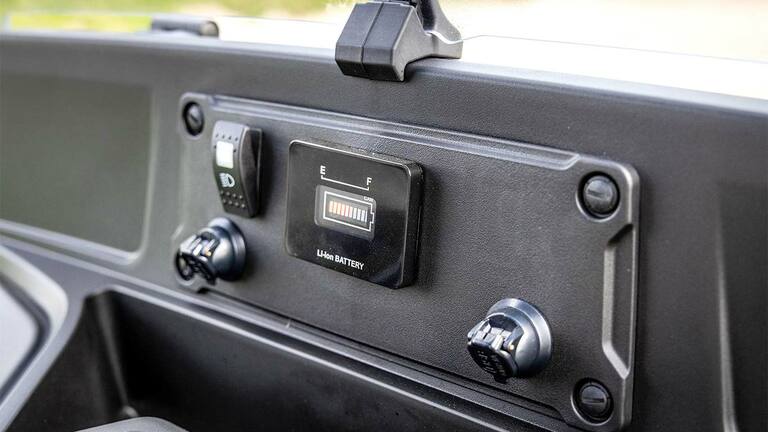 Instrumentpanel på en John Deere Gator GS elektrisk model, der viser batteriniveauindikator og strømporte.