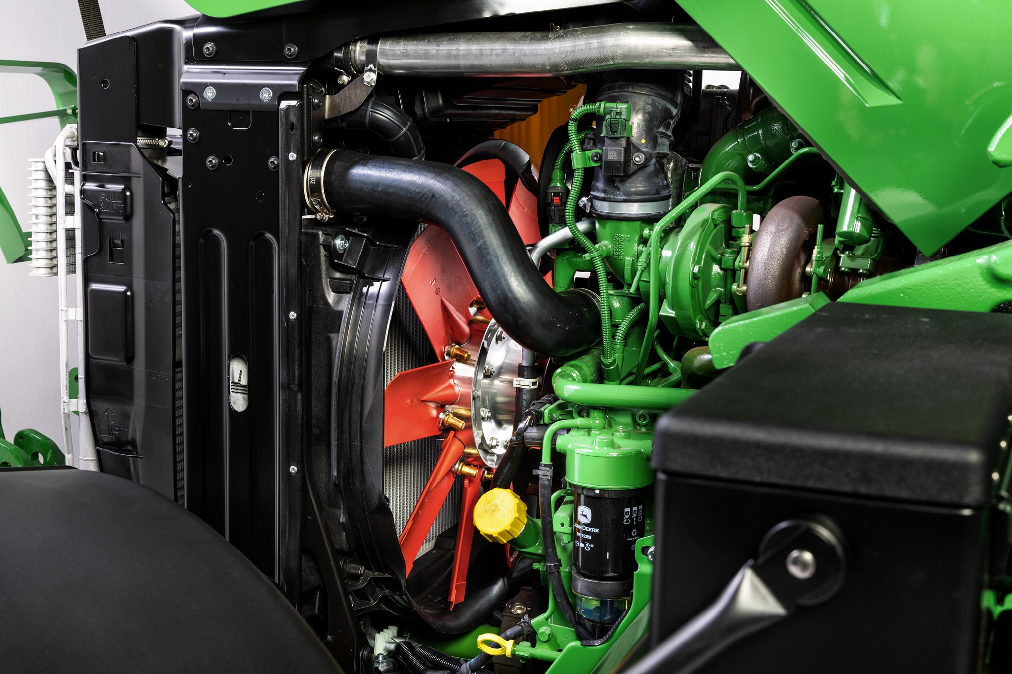 Nærbillede af motorrummet på John Deere 6M-serien med fokus på kølesystemet og motorkomponenterne.